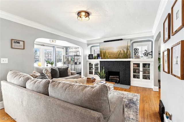 living area featuring ornamental molding, baseboards, a fireplace, and light wood finished floors