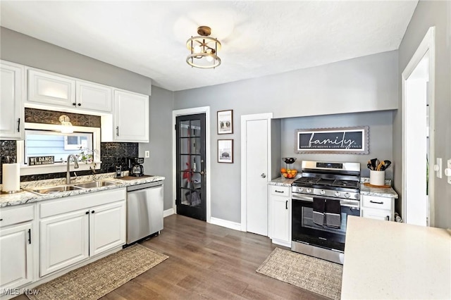 kitchen with appliances with stainless steel finishes, dark wood-style flooring, white cabinets, and tasteful backsplash