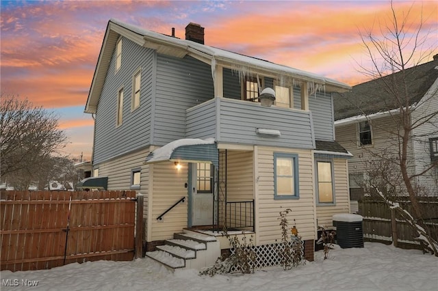 rear view of house with fence, a chimney, and central AC unit