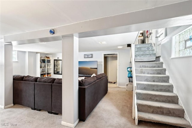 living area with light colored carpet, stairway, and baseboards