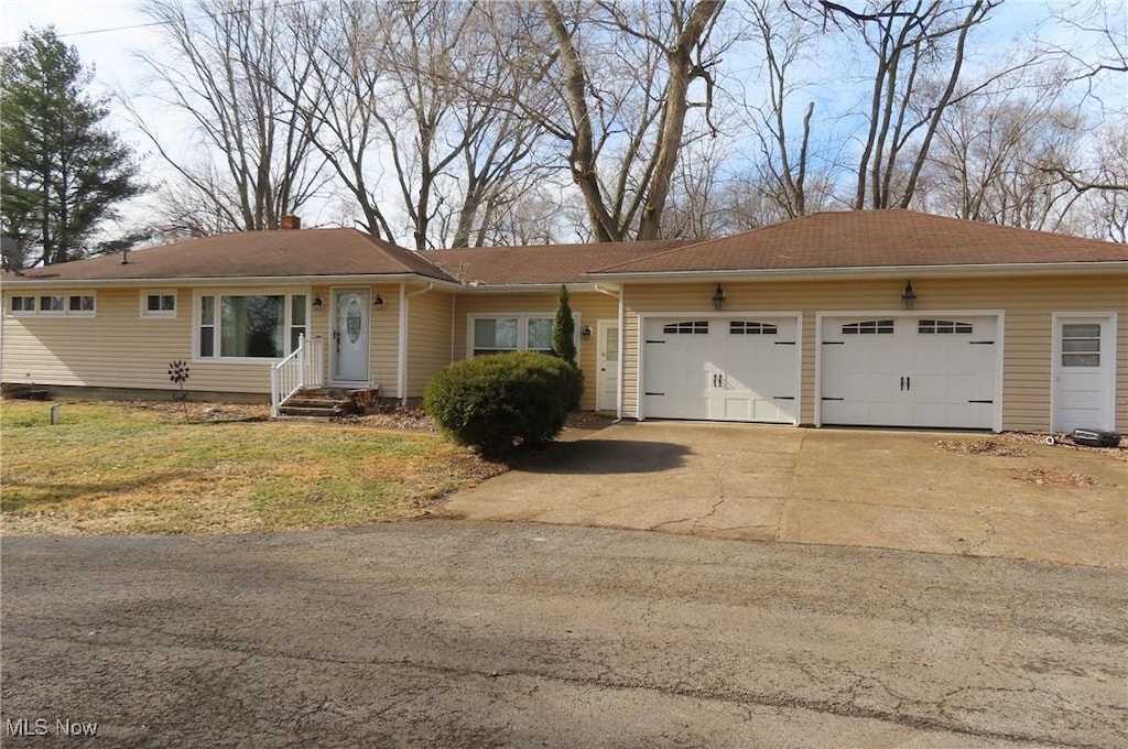 ranch-style house featuring driveway, a chimney, and an attached garage