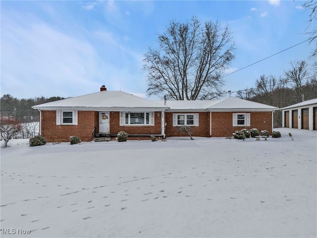 single story home featuring a garage, a chimney, and brick siding