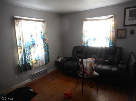 living room featuring wood finished floors, visible vents, and baseboards