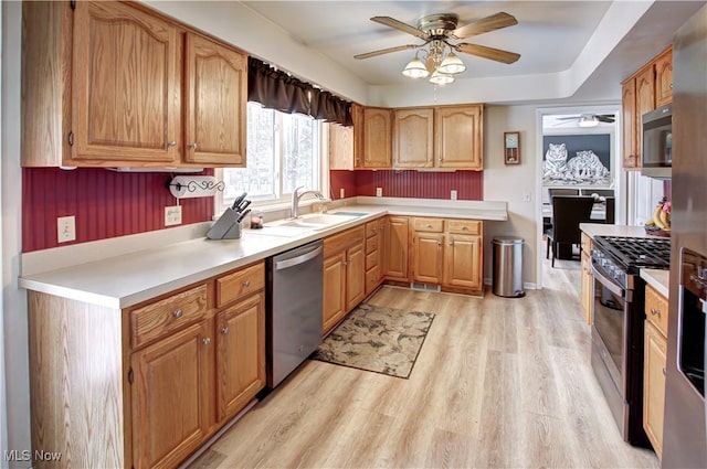 kitchen with stainless steel appliances, light countertops, a sink, and light wood-style flooring