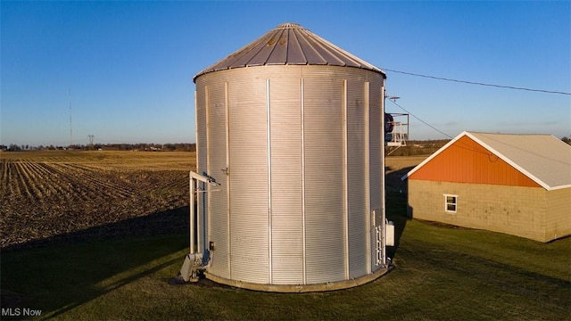 view of outdoor structure featuring central air condition unit, an outbuilding, and a rural view