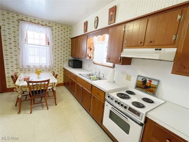 kitchen featuring wallpapered walls, white range with electric cooktop, light countertops, under cabinet range hood, and a sink