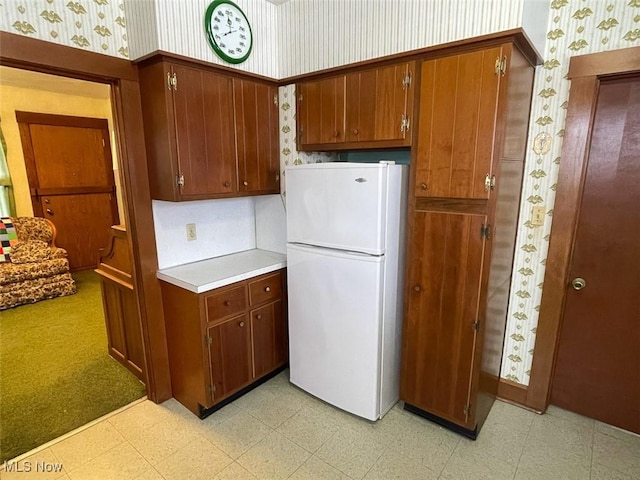 kitchen with wallpapered walls, light countertops, light floors, and freestanding refrigerator