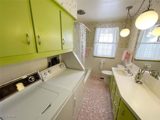 clothes washing area featuring a wainscoted wall, a sink, laundry area, independent washer and dryer, and wallpapered walls