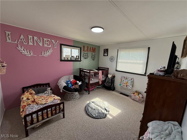 carpeted bedroom featuring a nursery area and visible vents