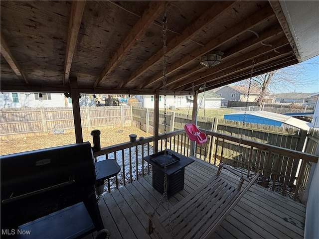 wooden deck with a fenced backyard and a grill