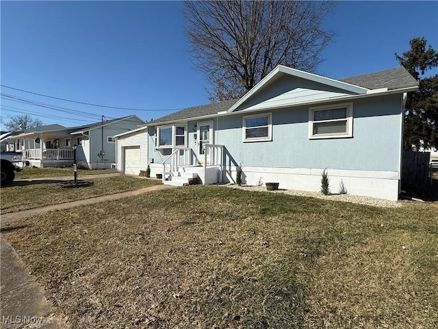 view of front of house with an attached garage, roof with shingles, and a front yard