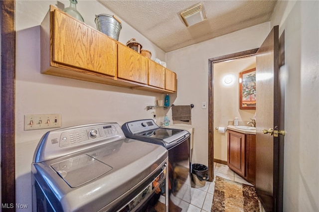 washroom featuring cabinet space, visible vents, a sink, a textured ceiling, and independent washer and dryer