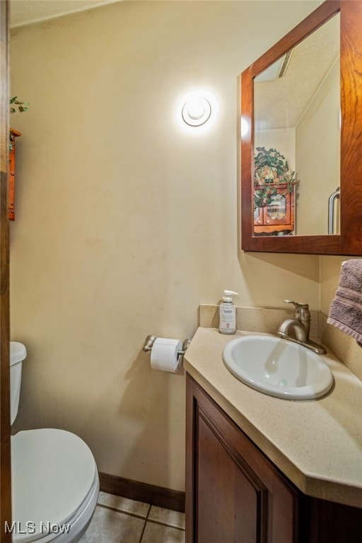 bathroom with toilet, baseboards, vanity, and tile patterned floors