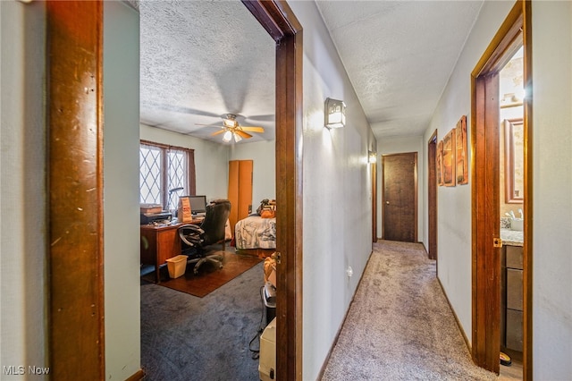 corridor featuring light carpet and a textured ceiling