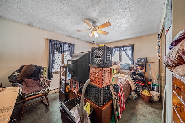 bedroom featuring ceiling fan, dark colored carpet, and a textured ceiling