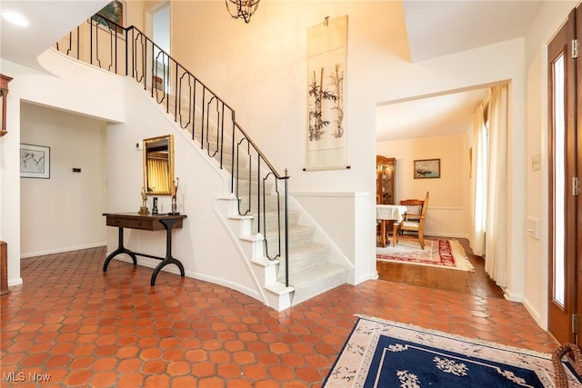 foyer with stairway, a towering ceiling, and baseboards