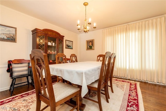 dining space with a notable chandelier, wood finished floors, and crown molding