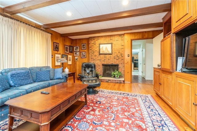 living area featuring a brick fireplace, beamed ceiling, wood walls, and light wood finished floors