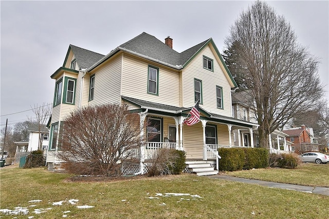 victorian house featuring a chimney, a front lawn, and a porch