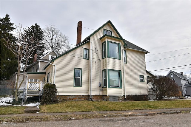 view of side of property featuring a yard, a chimney, and fence