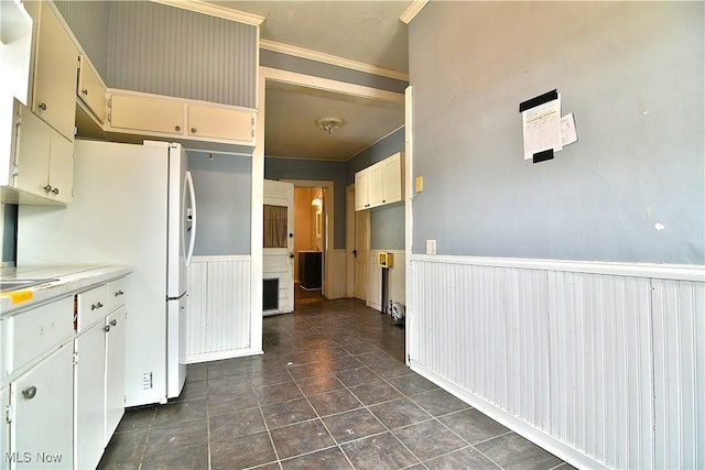 kitchen featuring a wainscoted wall, light countertops, dark tile patterned flooring, and crown molding