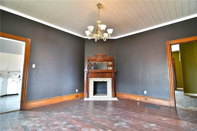 unfurnished living room featuring a chandelier, baseboards, ornamental molding, a brick fireplace, and dark wood finished floors