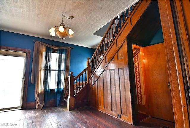 entryway with dark wood-style floors, crown molding, a notable chandelier, and stairs