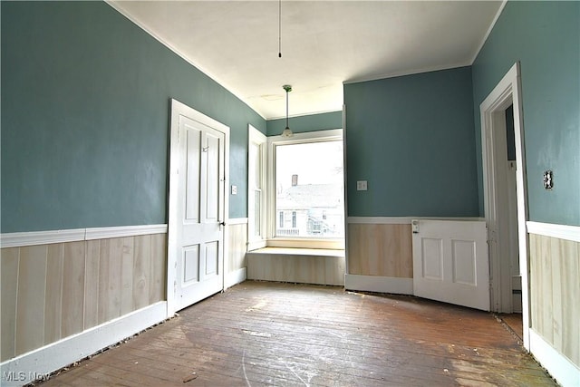 interior space featuring crown molding, a wainscoted wall, and dark wood finished floors