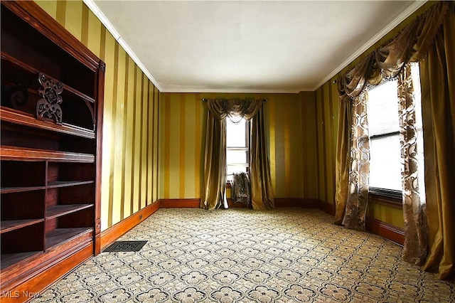 empty room with visible vents, crown molding, baseboards, and wallpapered walls