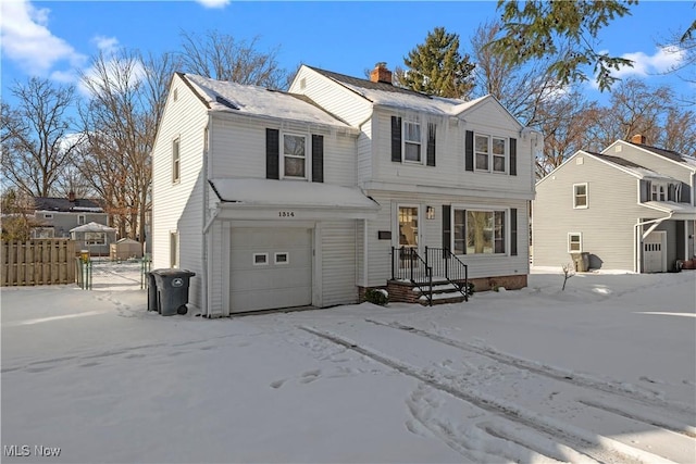 view of front of home featuring an attached garage, a chimney, and fence