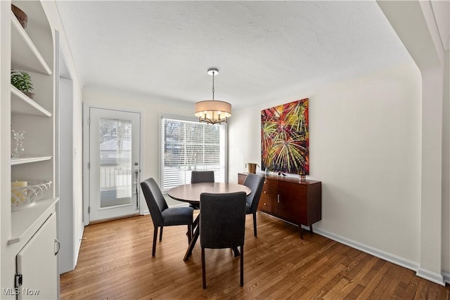 dining area featuring a notable chandelier, baseboards, and wood finished floors