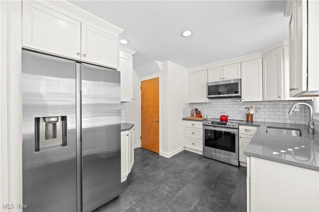 kitchen featuring recessed lighting, stainless steel appliances, a sink, white cabinetry, and decorative backsplash