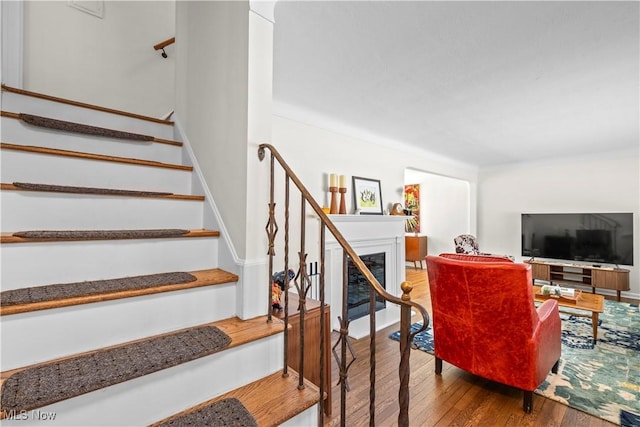 stairs featuring a fireplace and wood finished floors