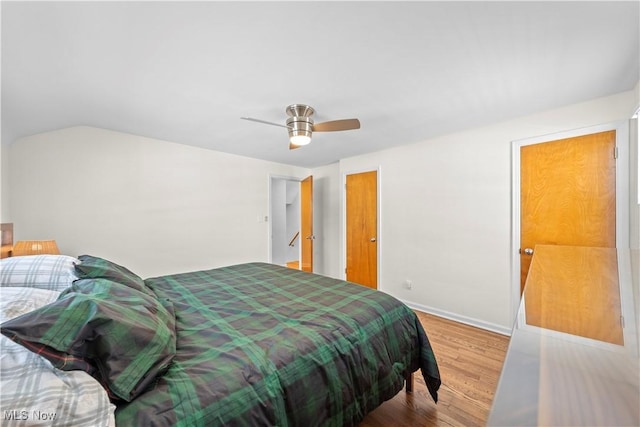 bedroom featuring lofted ceiling, a ceiling fan, baseboards, and wood finished floors