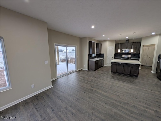 kitchen with a kitchen island, open floor plan, light countertops, appliances with stainless steel finishes, and hanging light fixtures