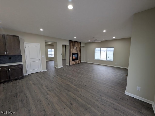 unfurnished living room with dark wood-style floors, recessed lighting, a tile fireplace, and a healthy amount of sunlight