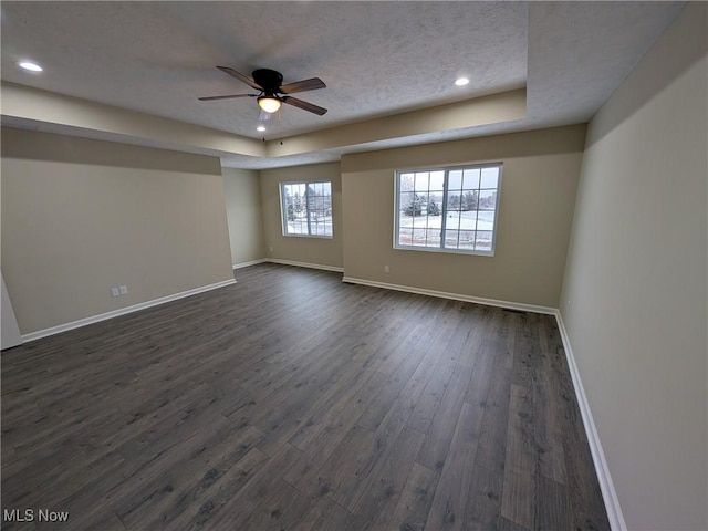 spare room with dark wood-style floors, ceiling fan, baseboards, and a textured ceiling