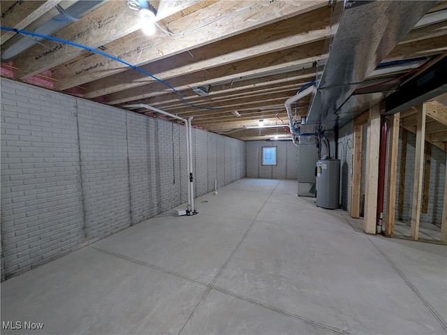 unfinished basement featuring brick wall and electric water heater