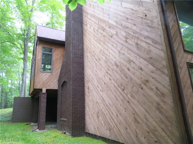 view of home's exterior with brick siding and a chimney