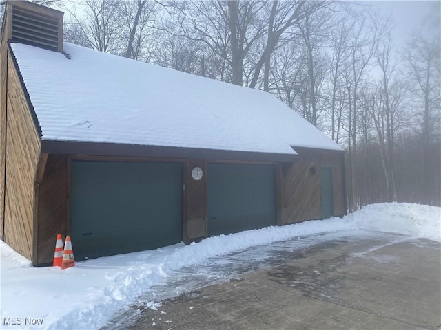 snow covered garage featuring a garage