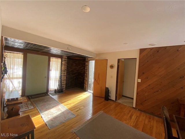 interior space featuring a fireplace, wooden walls, and light wood finished floors