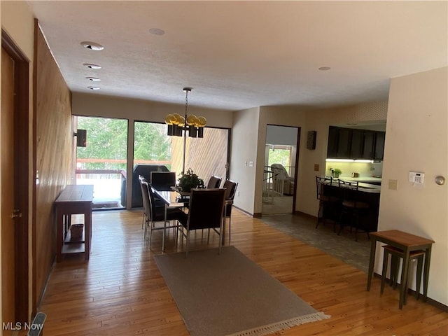 dining space with baseboards, a chandelier, and wood finished floors