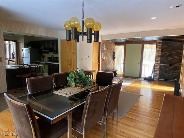 dining room with a notable chandelier, wallpapered walls, and light wood-style floors