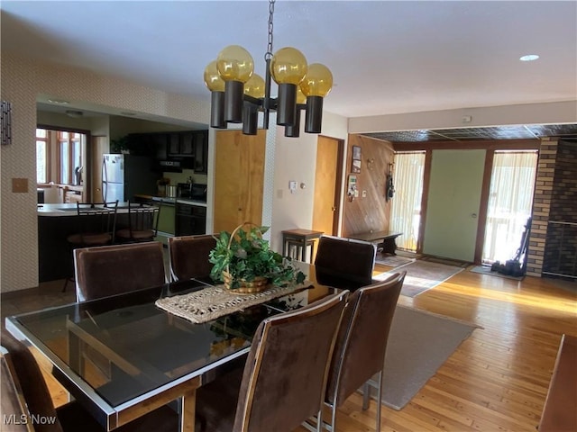 dining room featuring wallpapered walls, light wood-type flooring, and a notable chandelier