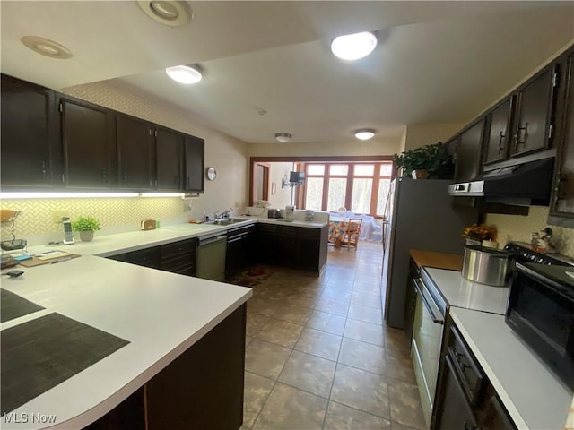 kitchen featuring a peninsula, dark brown cabinetry, light countertops, and backsplash