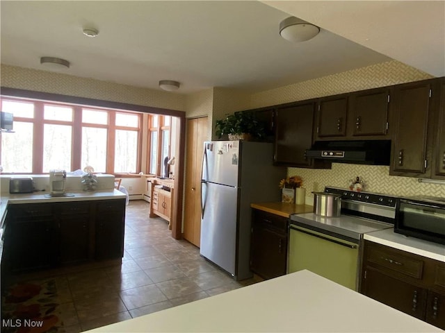 kitchen with electric stove, freestanding refrigerator, light countertops, under cabinet range hood, and black microwave