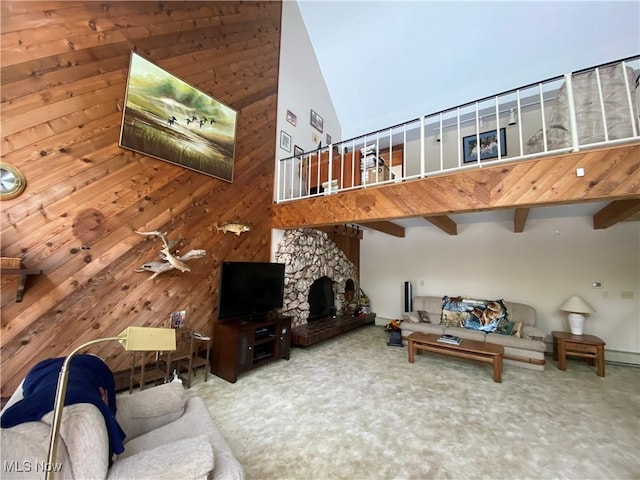 carpeted living room featuring a towering ceiling, wooden walls, and a stone fireplace