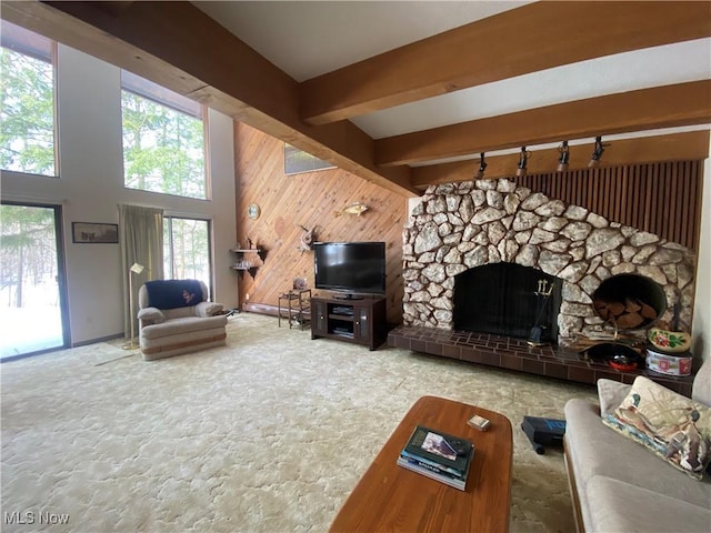 carpeted living room featuring high vaulted ceiling, wood walls, beamed ceiling, and a stone fireplace