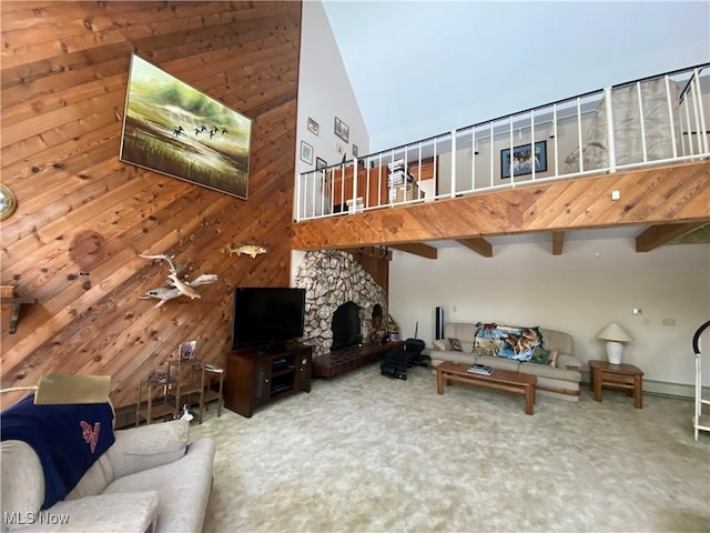 carpeted living room with a stone fireplace, a high ceiling, and wooden walls