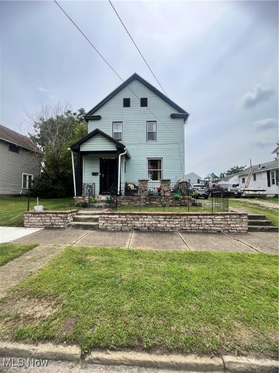 traditional home with a fenced front yard and a front lawn